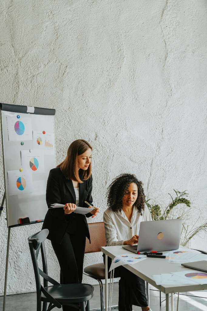 Two women collaborating with charts and a flipchart